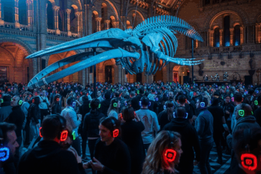 A captivating shot of a silent disco taking place beneath a colossal whale skeleton in a historic London museum, with participants wearing headphones that glow in various colors, showcasing the innovative and popular silent disco events in London.